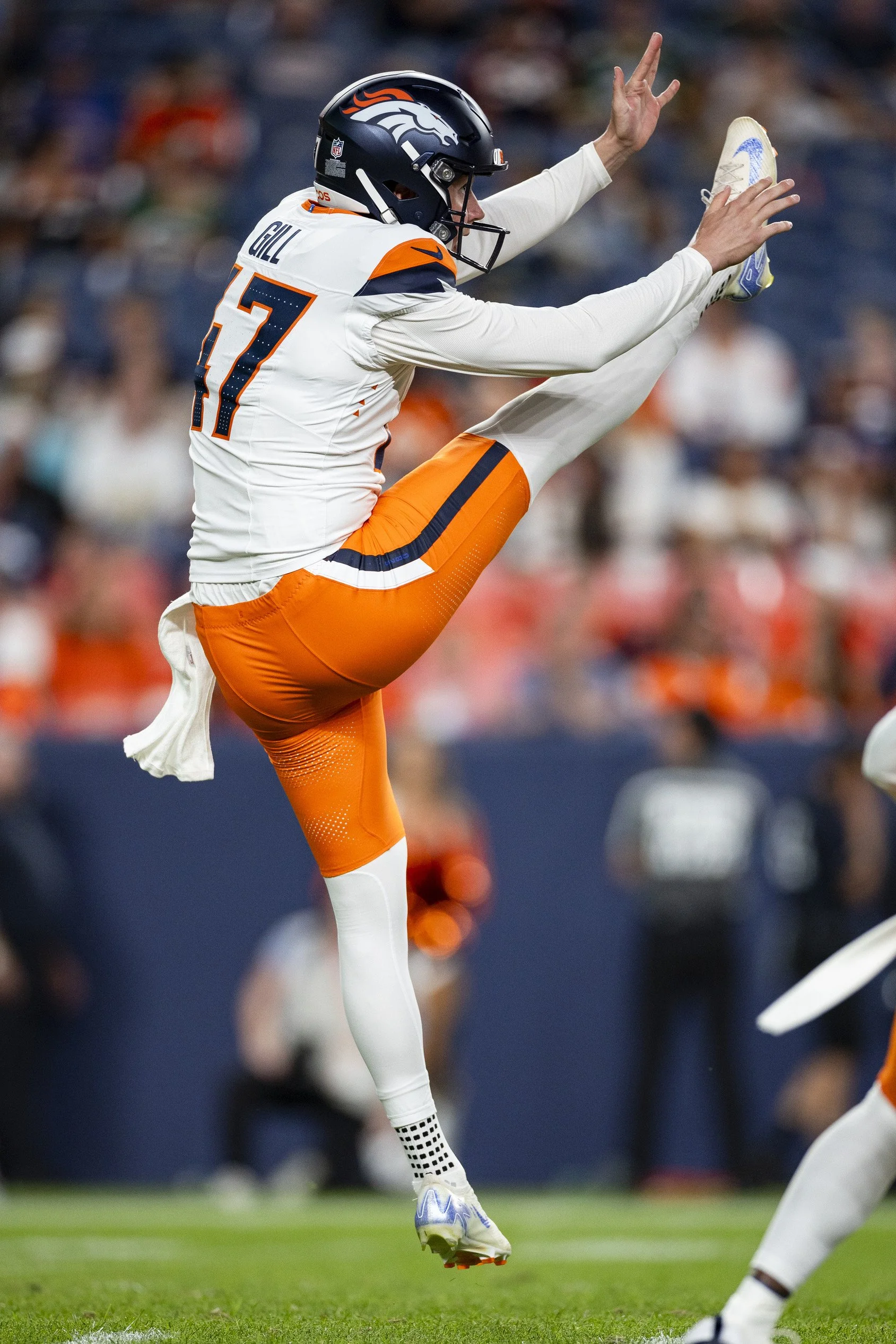 Football player in uniform executing a high jump catch on the field, with crowd in the background.